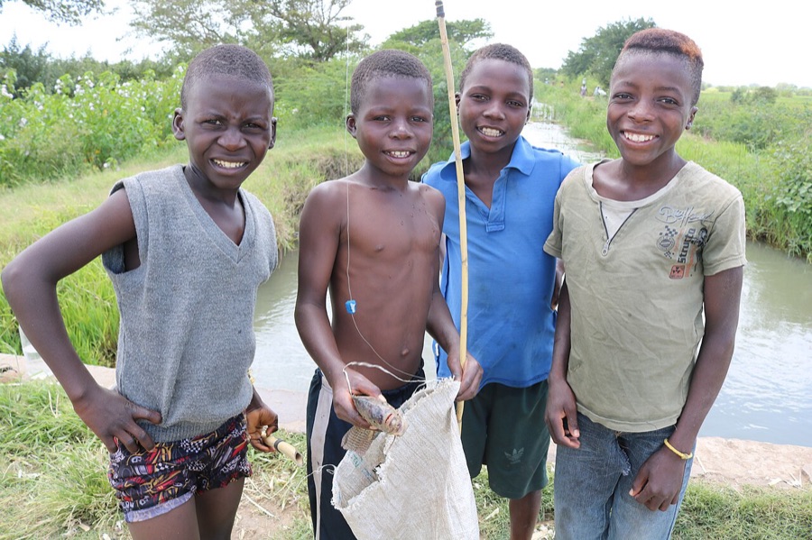 Quatro meninos sorrindo depois da pescaria num riacho em Moçambique